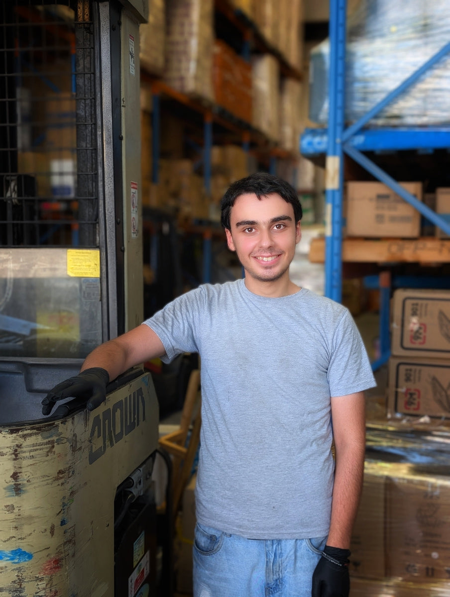 Man standing next to a forklift in a warehouse setting