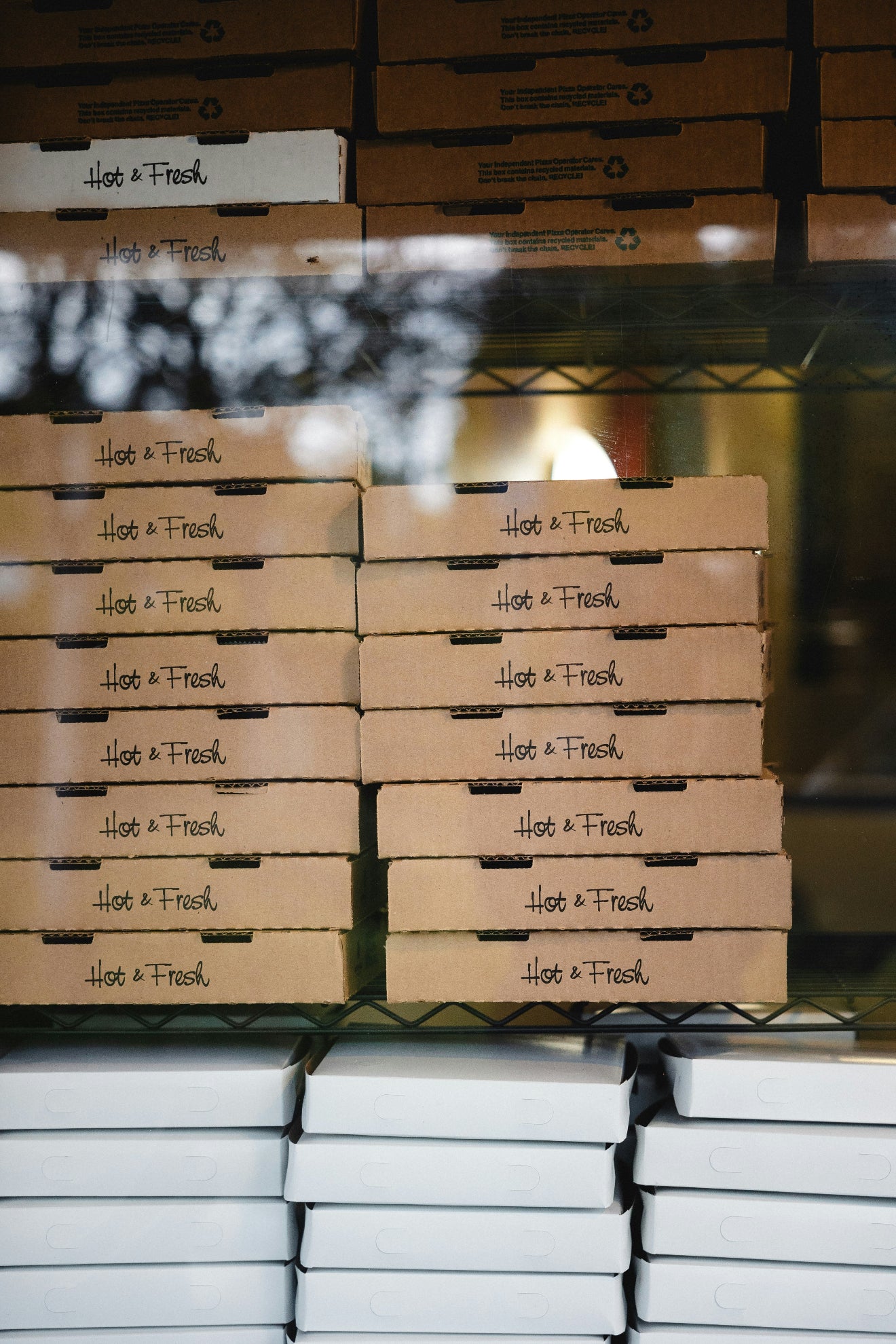 Stacks of 'Hot & Fresh' branded boxes on a metal rack.