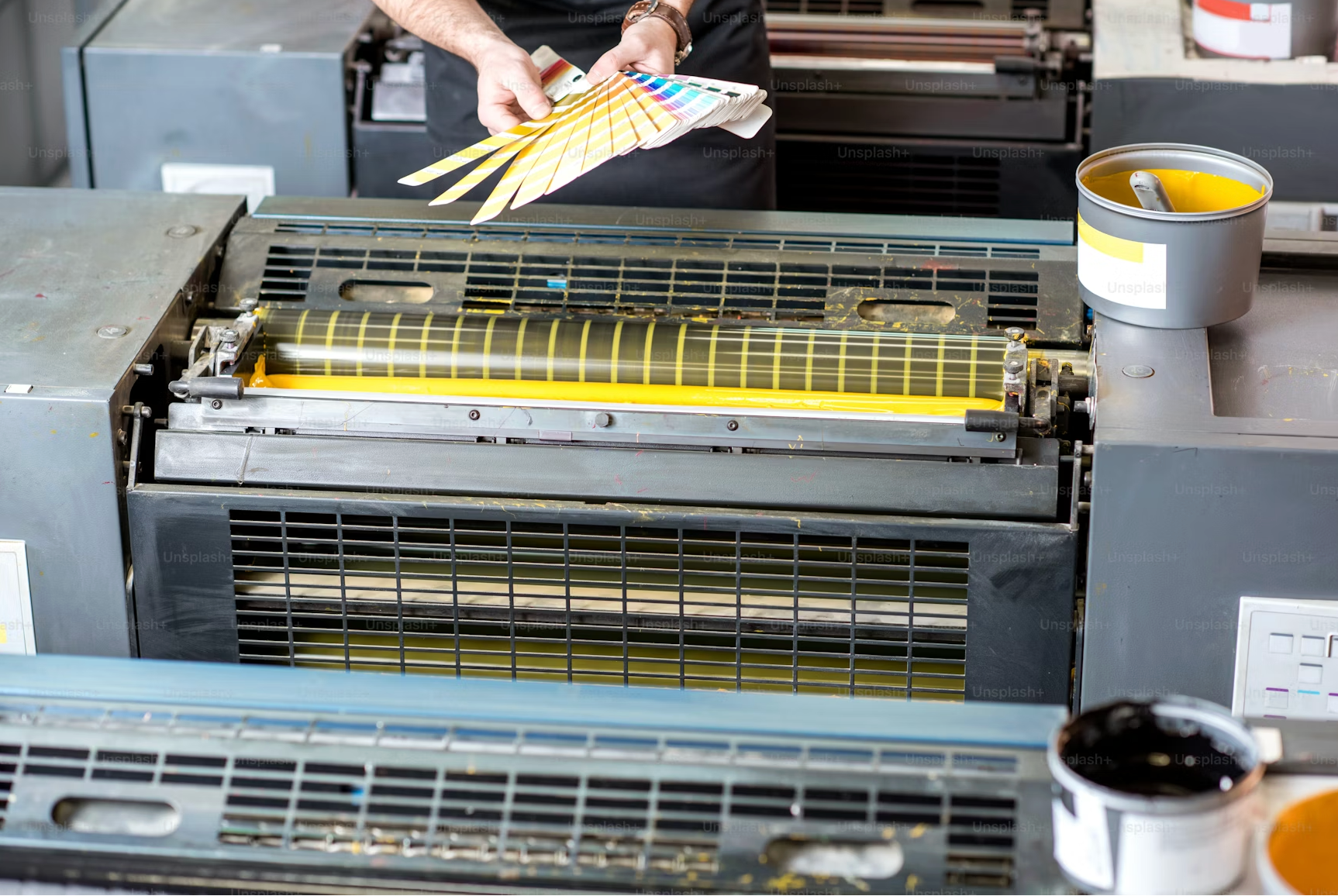 Person working with printing equipment and color swatches in a print shop.