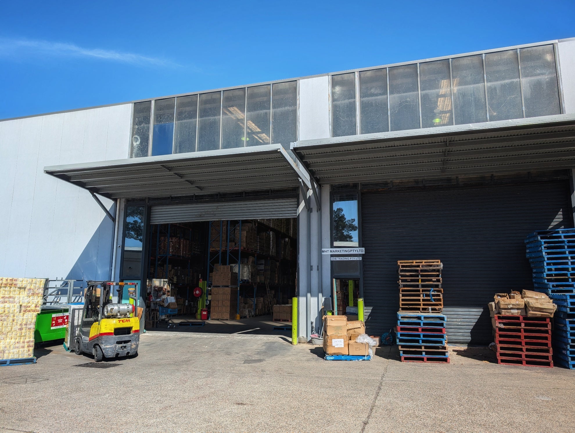 MHT Silverwater Warehouse exterior with forklift, pallets, and boxes on a clear day