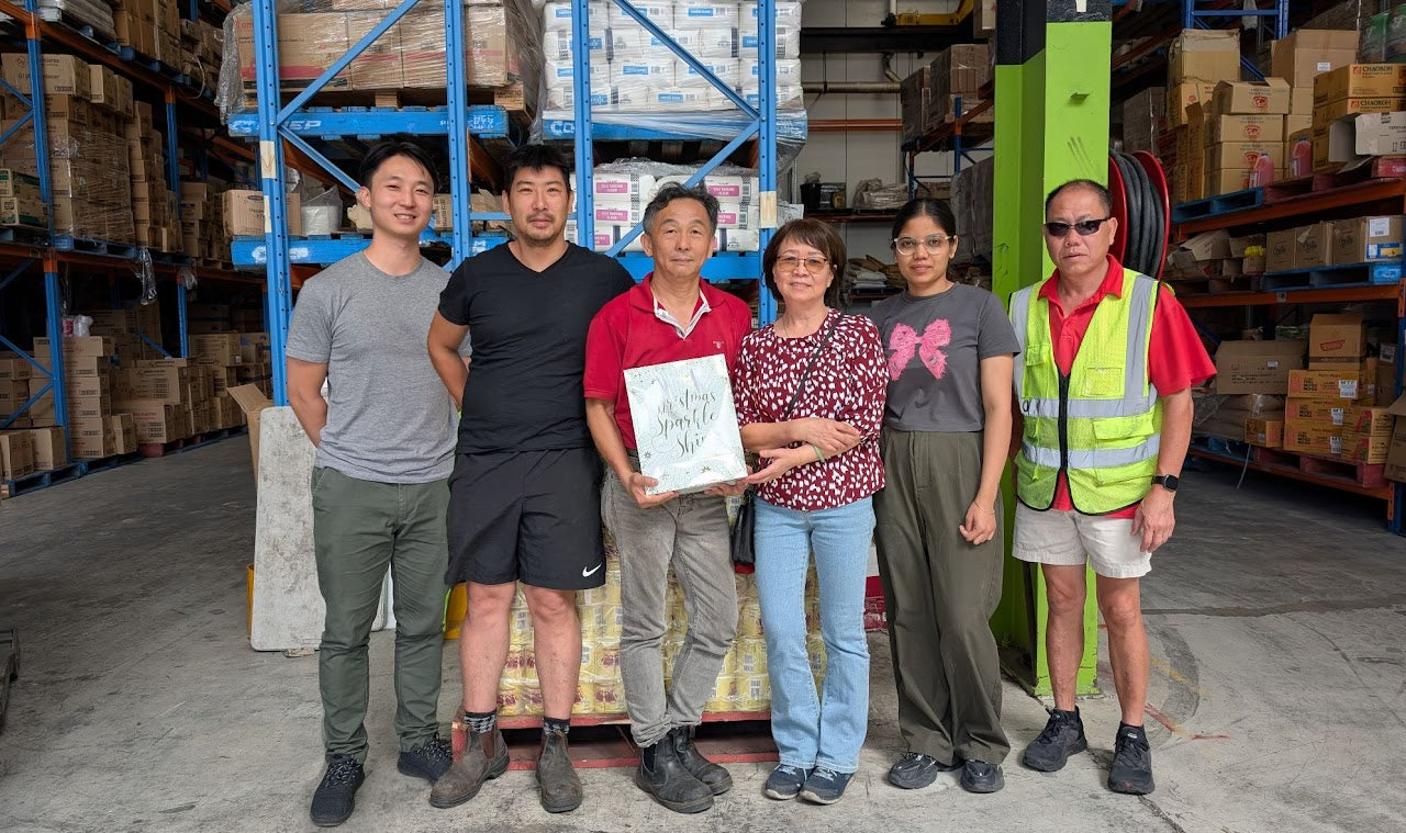 Group of people standing in a warehouse with shelves and boxes in the background